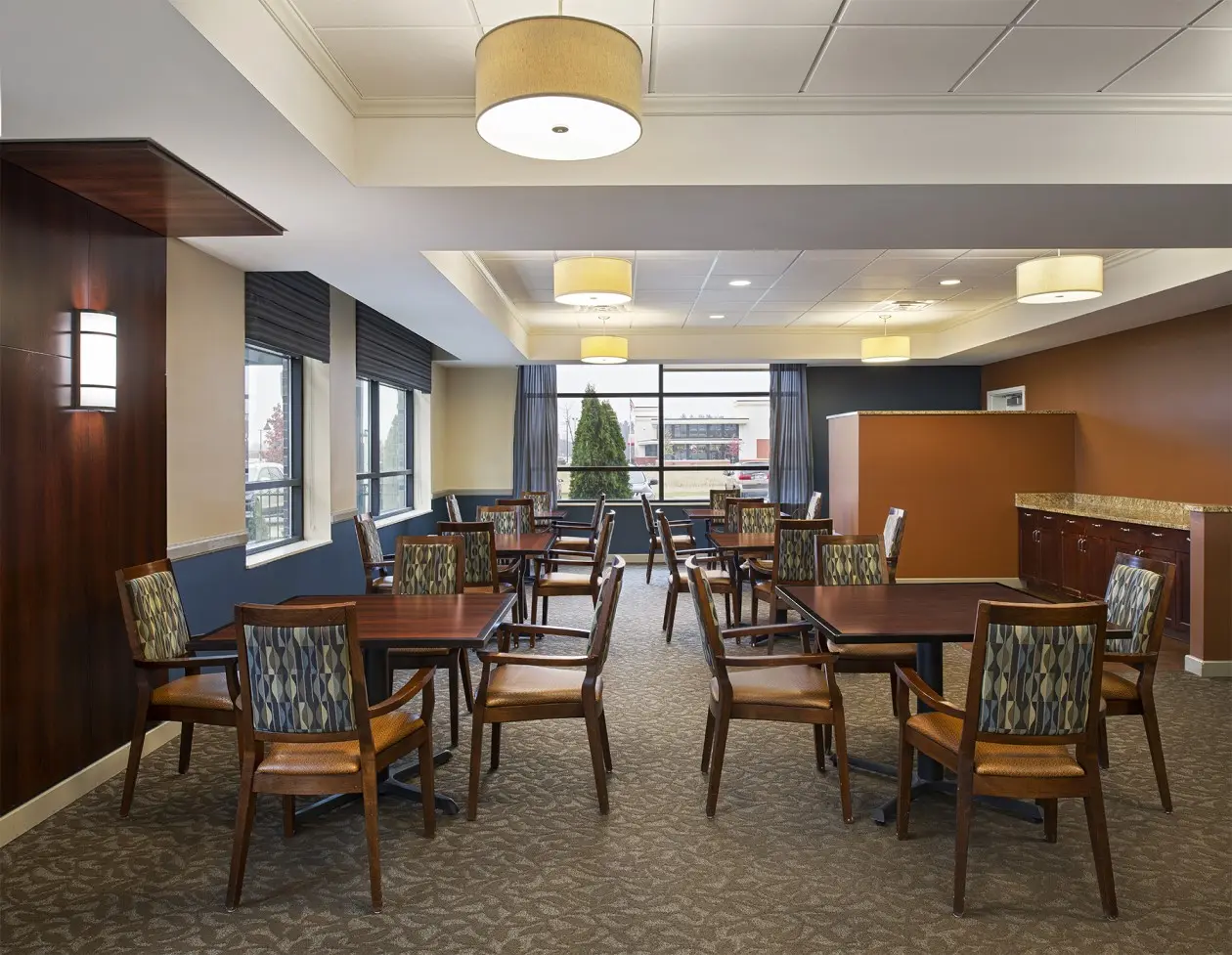 Dining area with large windows in memory care apartments at American House in Wyoming, MI